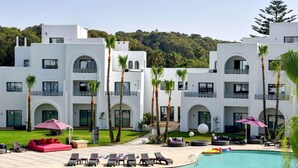 Ein Resort mit Schwimmbad, Liegestühlen und Palmen.