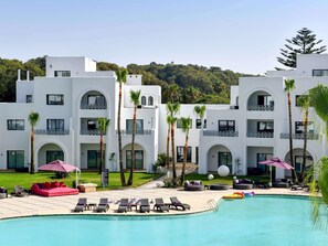 Un resort con piscina, lettini e palme.