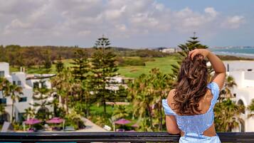 A person overlooking a golf course with a pool and resort buildings in the background.