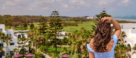 A person overlooking a golf course with a pool and resort buildings in the background.