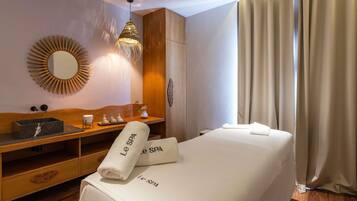 Une salle de spa avec un meuble-lavabo en bois, un miroir, un luminaire suspendu et un lit agrémenté de serviettes étiquetées « Le SPA ».