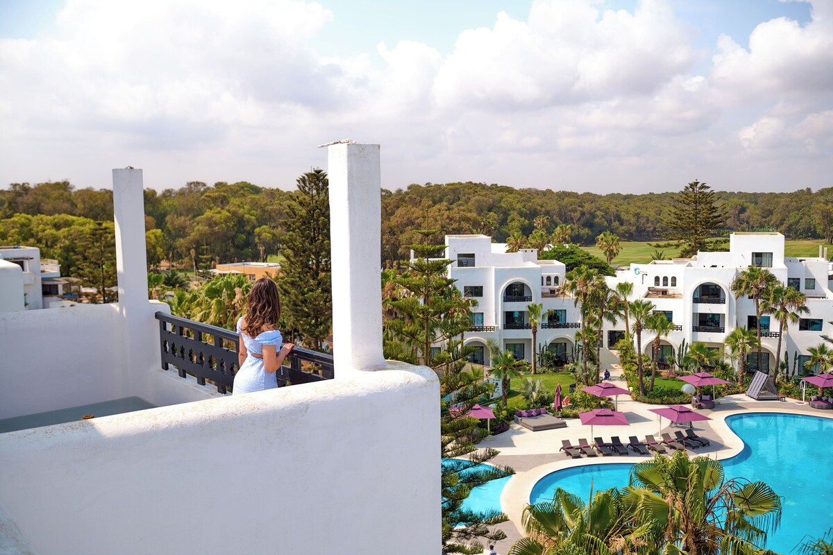 Un resort con piscina, palmeras y vistas del paisaje circundante.