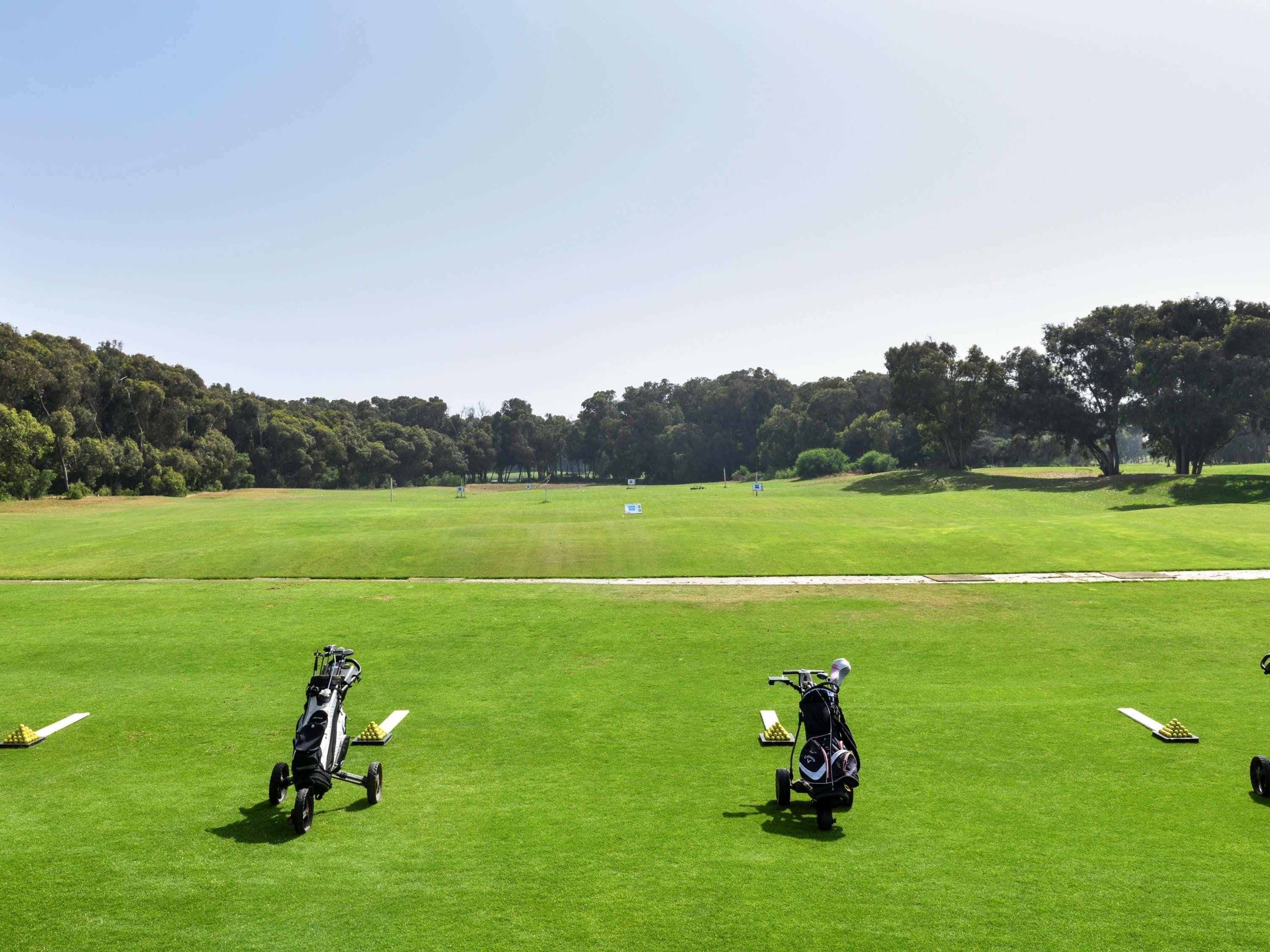 A golf course with two golf carts and a clear sky.