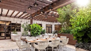 An outdoor patio with a wooden pergola, wicker furniture, and potted plants. - The Ritz-Carlton Coconut Grove, Miami (Miami)