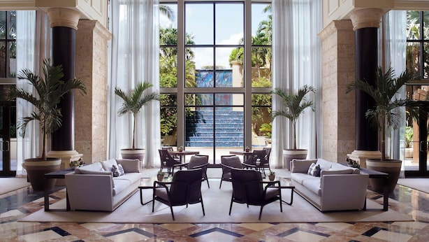 Un hall d’entrée spacieux, doté d’un grand espace salon, d’un magnifique lustre et offrant une vue sur un élément décoratif aquatique situé à l’extérieur.