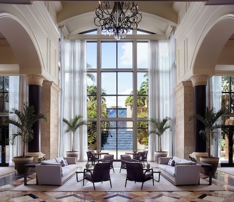 A spacious lobby with a large seating area, a grand chandelier, and a view of a water feature outside.