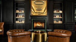 Un salon luxueux avec une cheminée, des fauteuils en cuir et des étagères à livres.