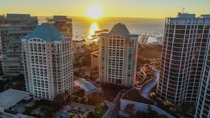 Un hôtel de grande hauteur doté d’une piscine et offrant une vue sur le coucher de soleil sur l’océan.