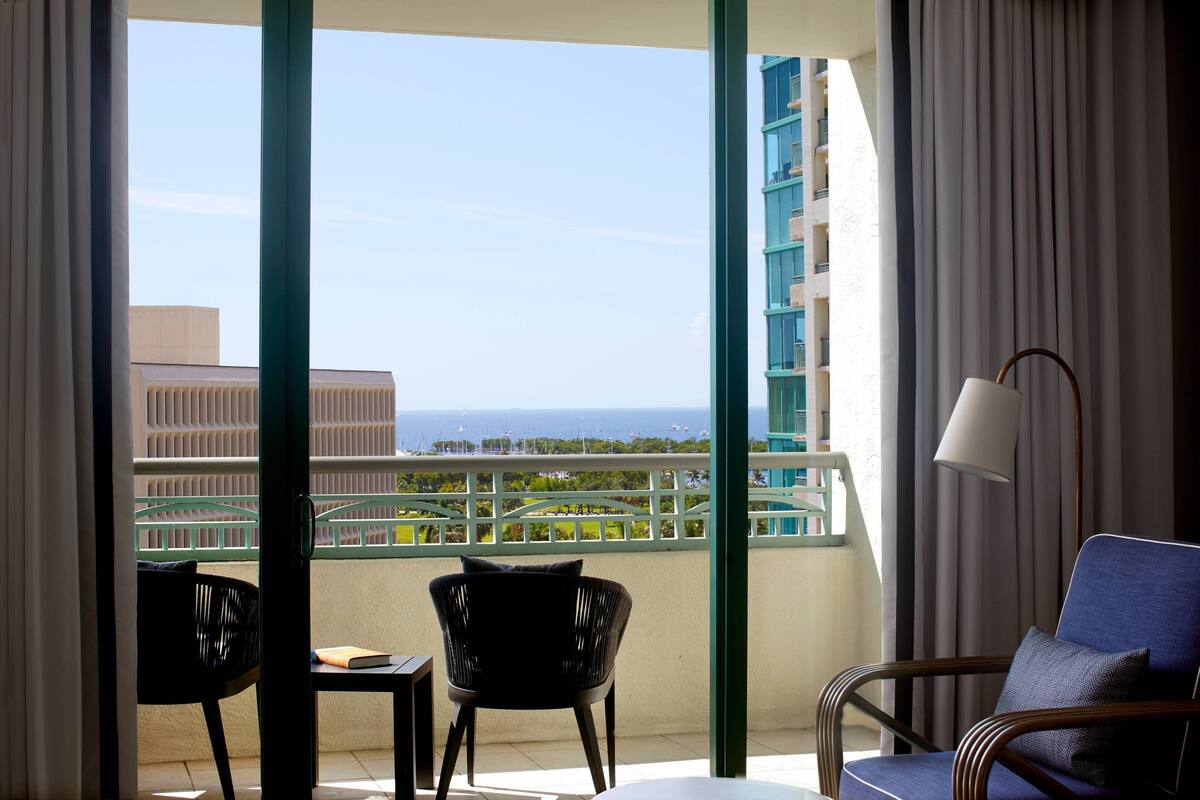 A balcony with two chairs, a table, and a lamp.