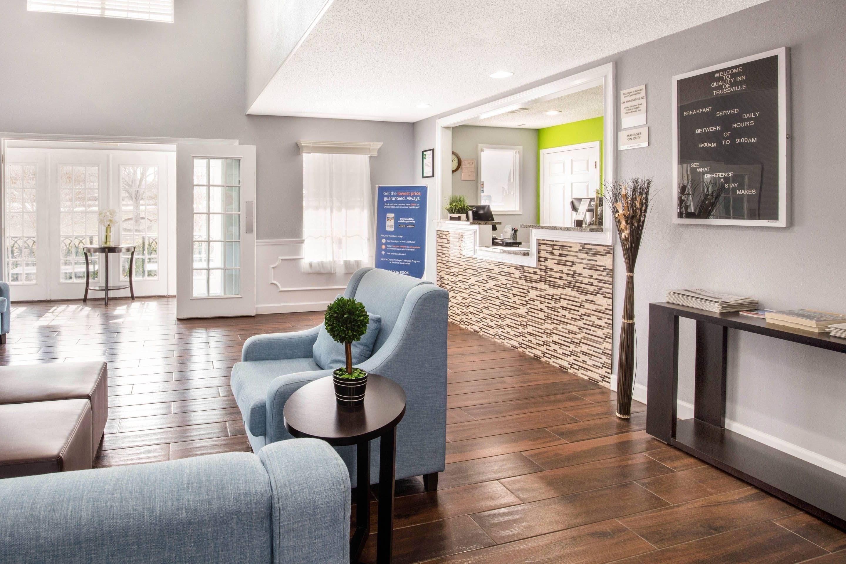 A modern hotel lobby with a reception desk, seating area, and a view of the city.