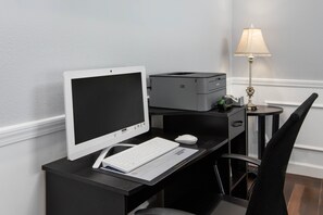 Een modern bureau met een computer, printer, toetsenbord, muis en een lamp.