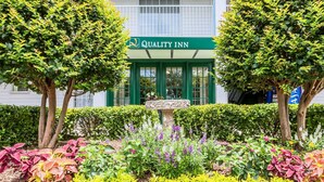 A building with a sign reading "Quality Inn" and a well-maintained garden with various plants and a central fountain. - Quality Inn Trussville I-59 exit 141 (Trussville)