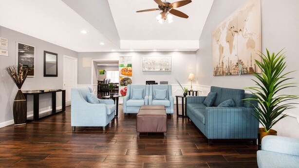 A spacious living room with a high ceiling, a ceiling fan, and a world map on the wall. - Quality Inn Trussville I-59 exit 141 (Trussville)