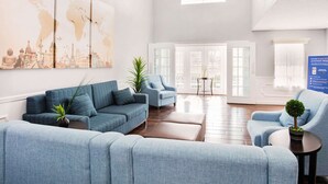A spacious living room with a large world map mural, a blue sofa set, a coffee table, and a small potted plant. - Quality Inn Trussville I-59 exit 141 (Trussville)