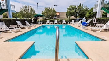 A rectangular swimming pool with a central diving board, surrounded by white lounge chairs and a lifebuoy.