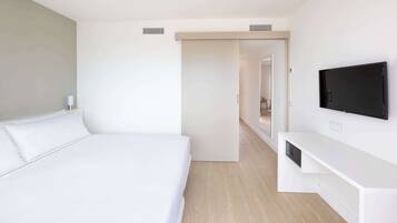 Una habitación de hotel moderna con una cama grande, un televisor de pantalla plana montado en la pared y un vestidor.