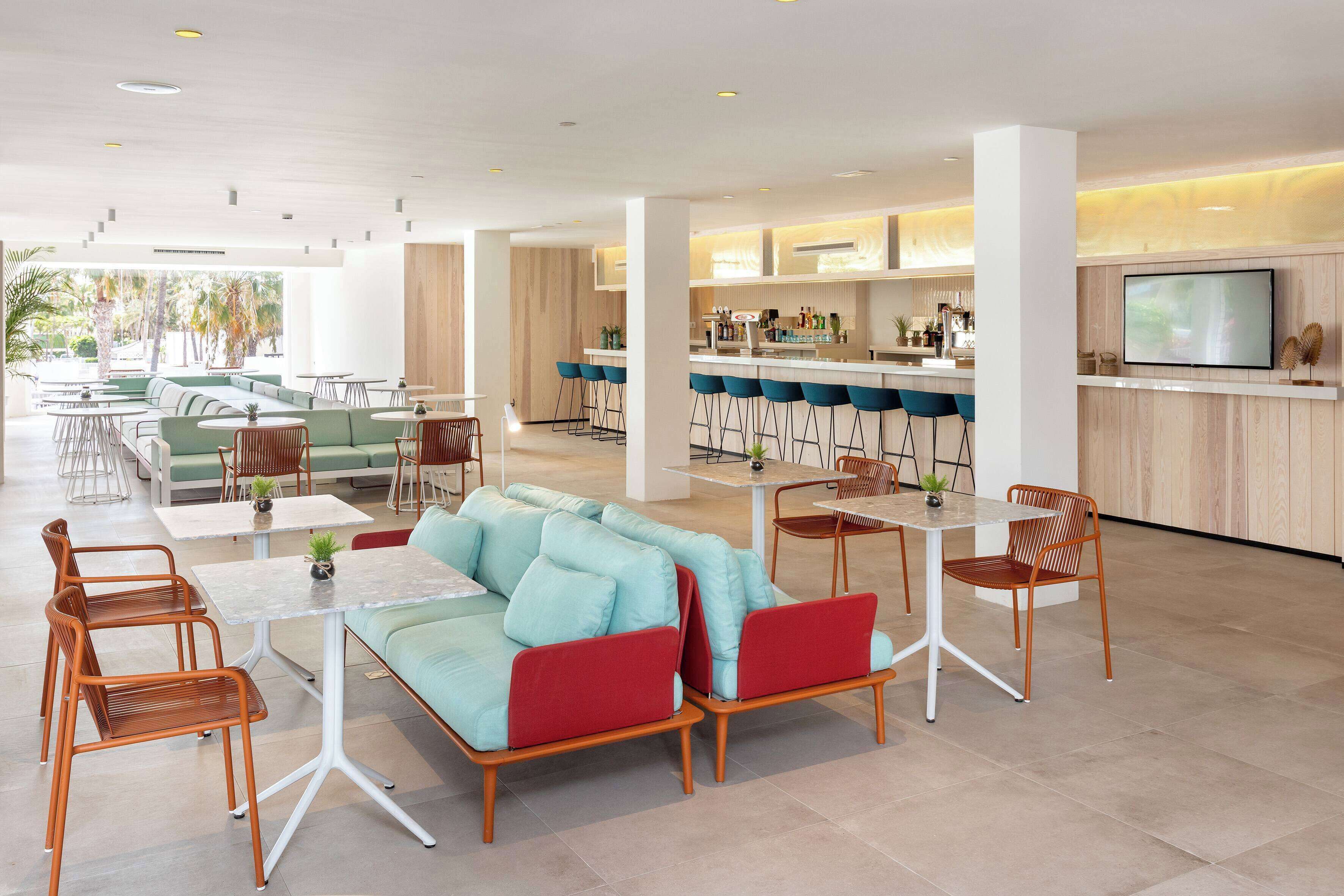 Un espace de détente moderne comprenant un canapé, des fauteuils et un coin bar avec un téléviseur.