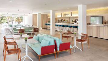 Un espace de détente moderne comprenant un canapé, des fauteuils et un coin bar avec un téléviseur.