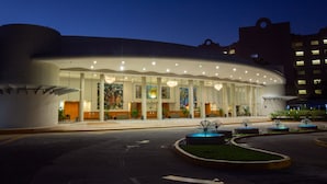 Hotel moderno com fachada curva, grandes janelas e área de entrada bem iluminada.