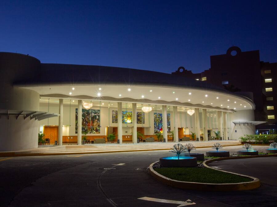 Un hotel moderno con fachada curva, amplias ventanas y un área de entrada bien iluminada.