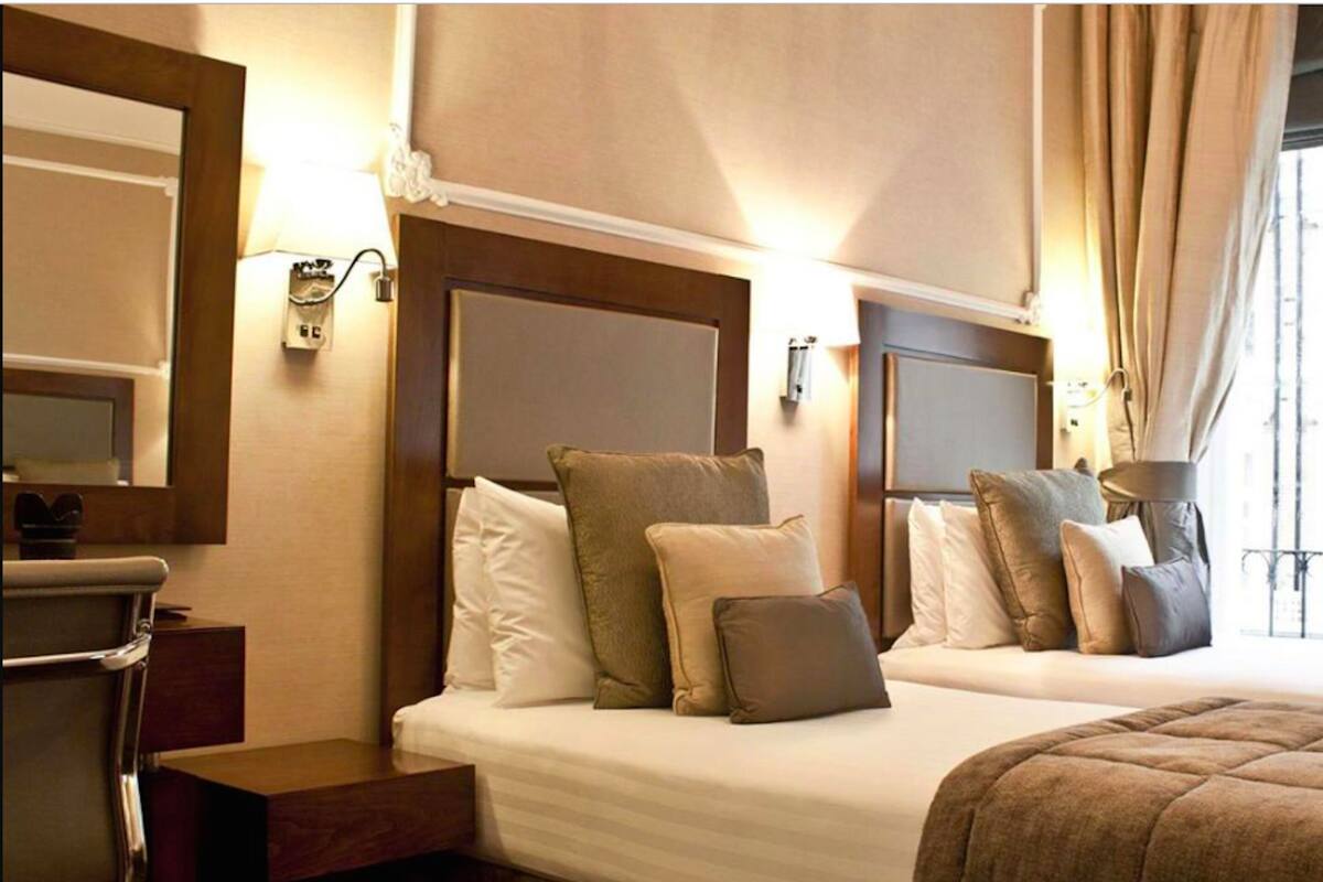 Ein Hotelzimmer mit zwei Betten, einem Schreibtisch und einem Spiegel.