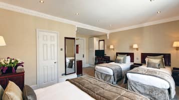 A hotel room with two beds, a desk, a chair, a TV, and a mirror.