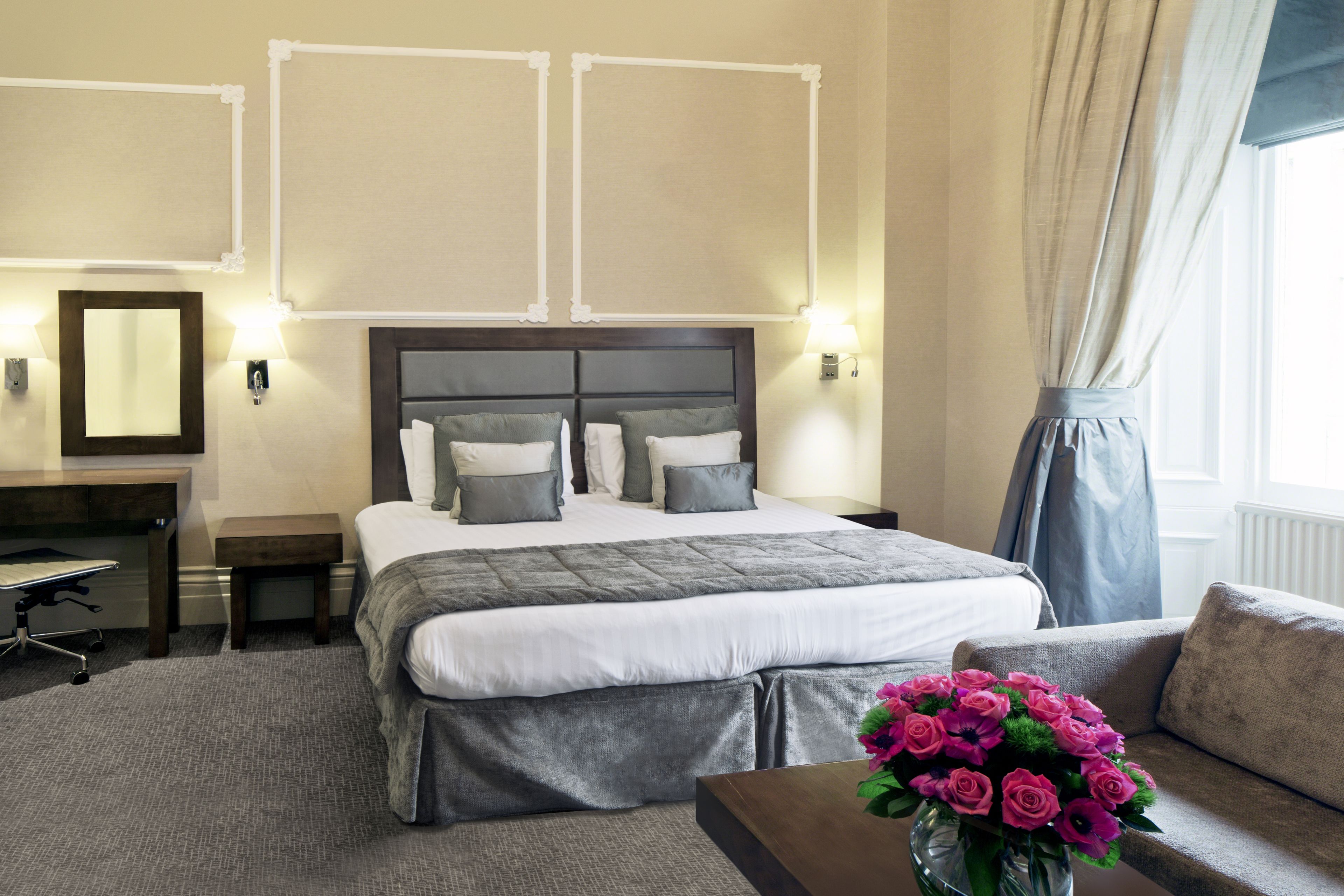 A hotel room with a large bed, a desk, and a sofa.