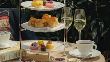 A tiered dessert stand with various pastries and a cup of tea on a table.