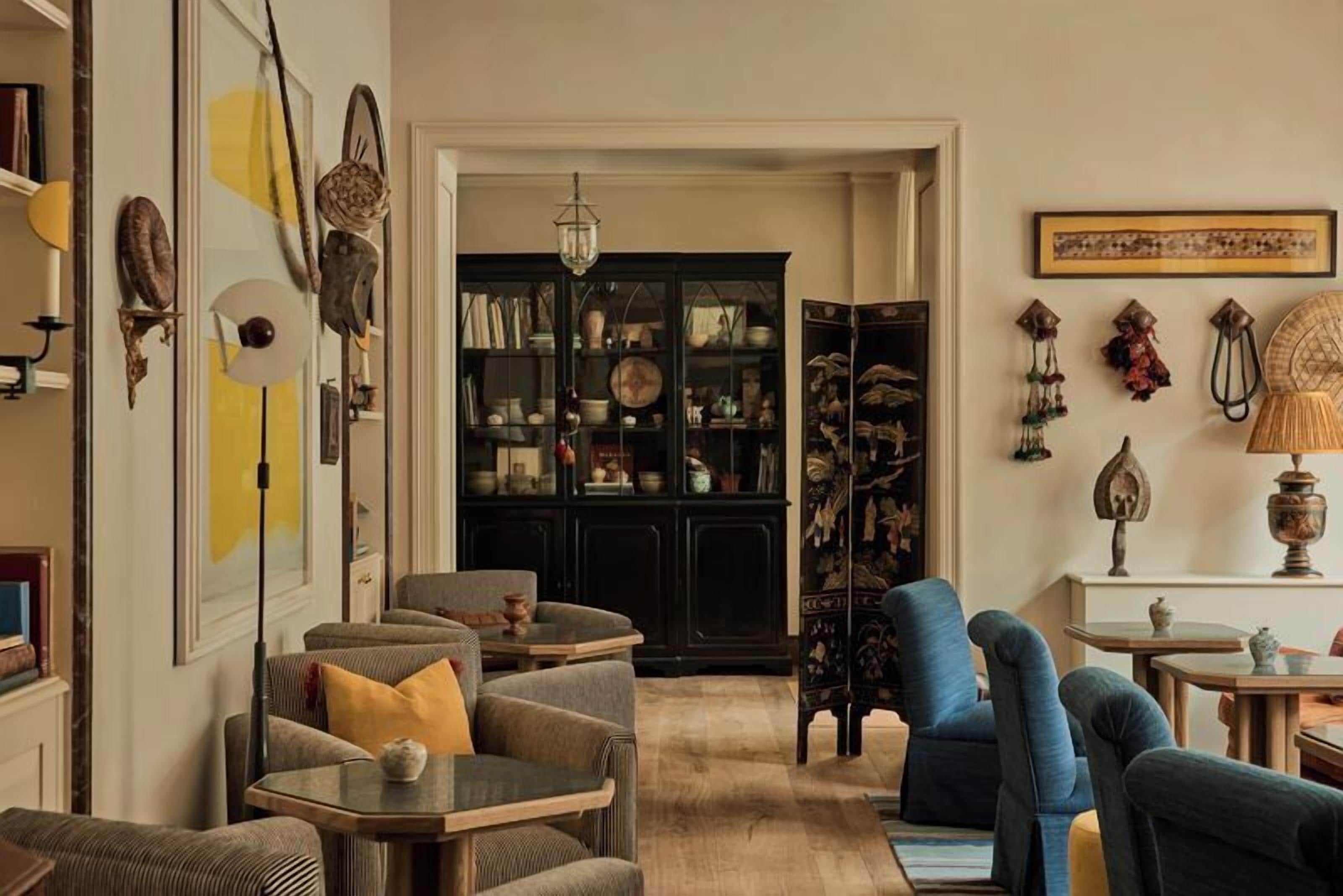 Un salon comprenant un canapé, des fauteuils, une table basse, une bibliothèque et une lampe.