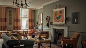 Un salon doté d’une cheminée, d’un lustre et d’un grand tableau abstrait.