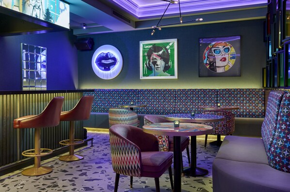 A bar area with stools, a couch, and a patterned wall.