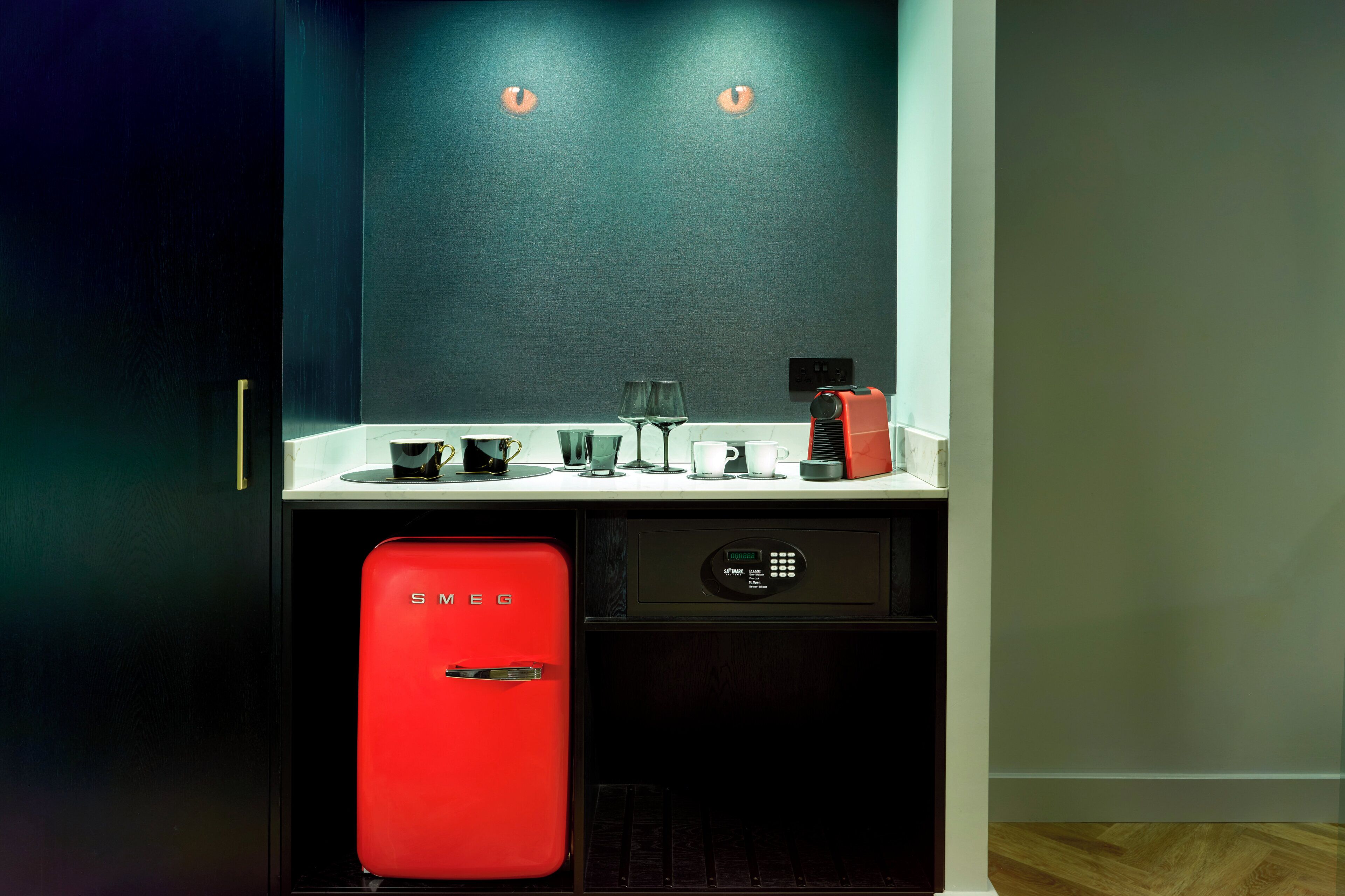 A compact kitchen with a red appliance, a coffee maker, and a wine glass on the counter.