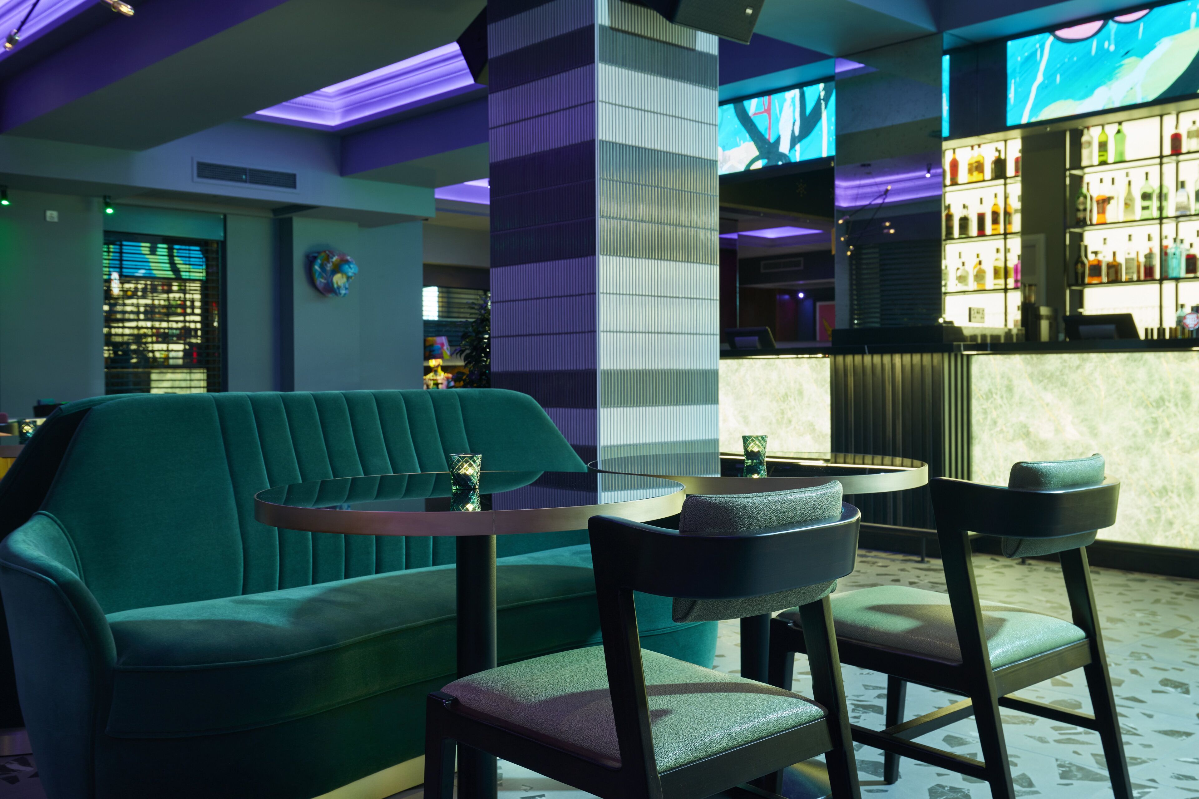 A bar area with a green sofa, two chairs, and a small round table.
