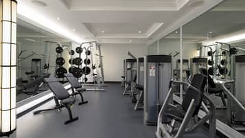 Un gimnasio moderno con paredes de espejo, equipo de levantamiento de pesas y bancos.