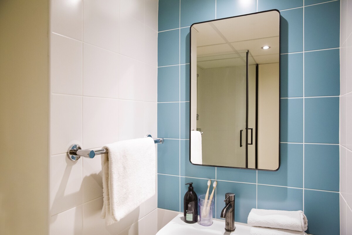 A bathroom with a white sink, a mirror, a towel rack, and a blue tiled wall.