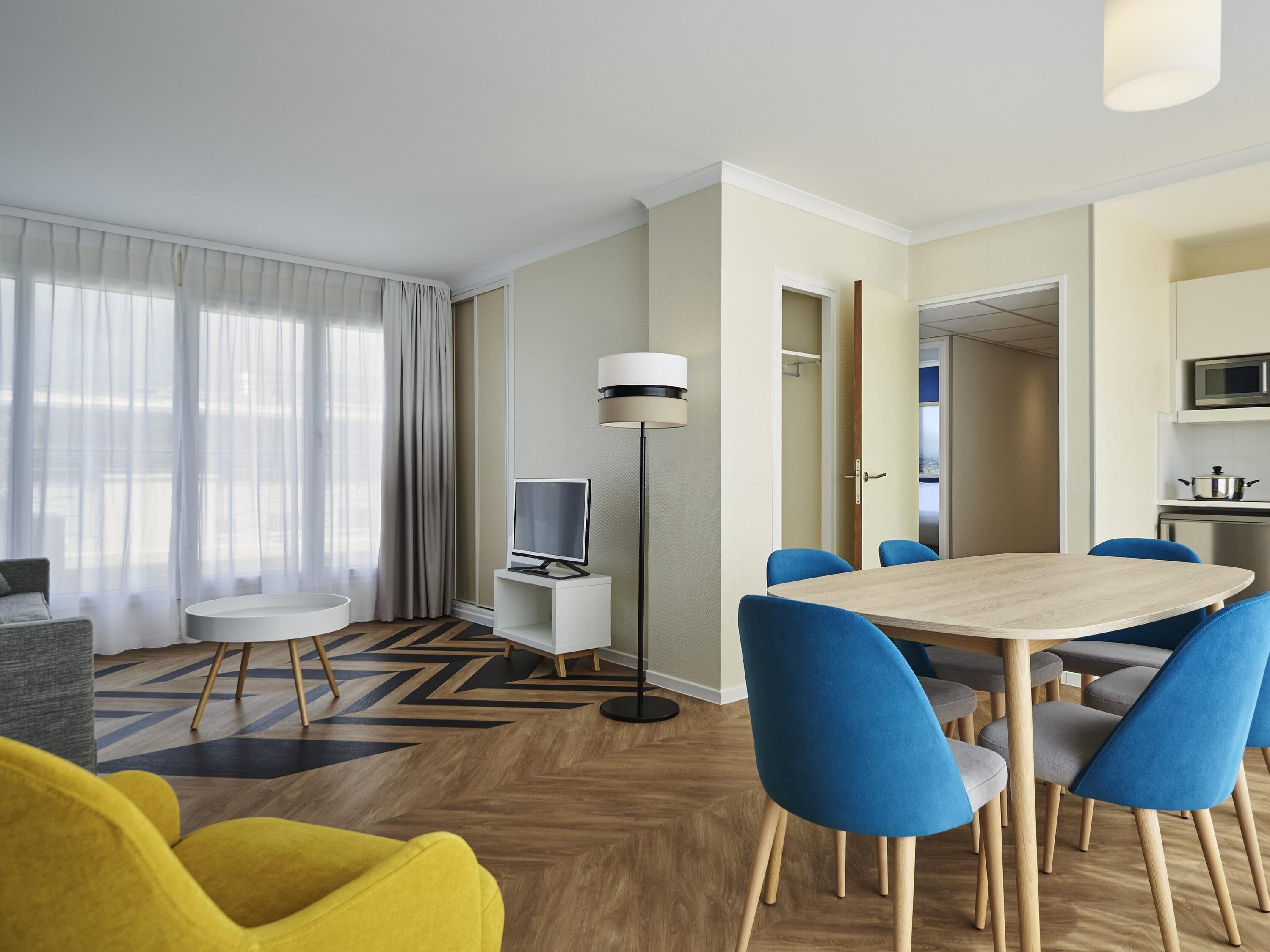 Une chambre d’hôtel moderne dotée d’un coin repas, d’un téléviseur à écran plat, d’un four à micro-ondes et offrant une vue sur l’extérieur par une porte.