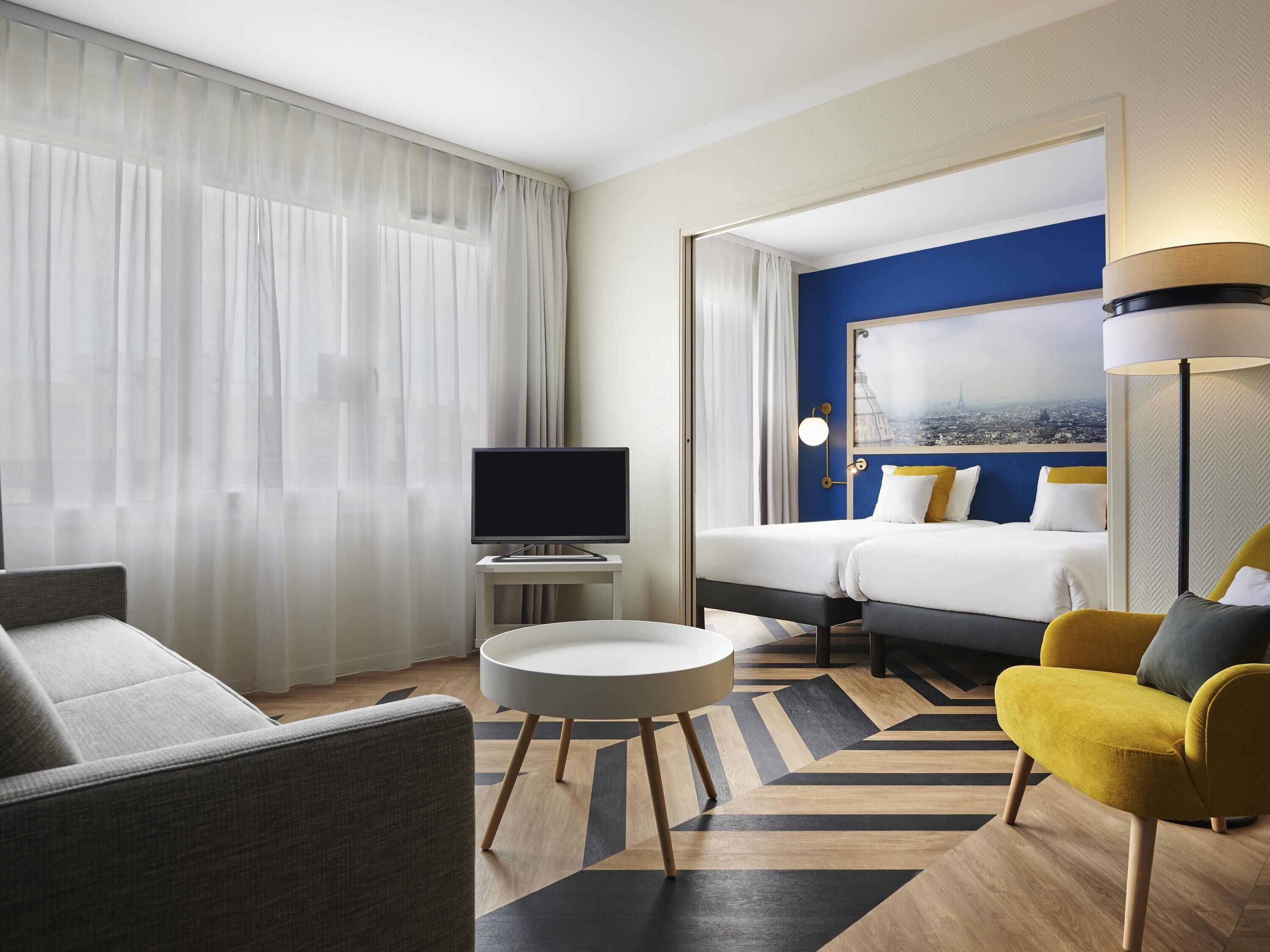 Een hotelkamer met een bed, een televisie, een ronde tafel, een bank en een stoel.