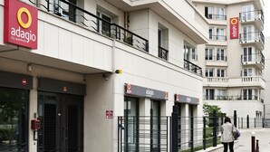 A city apartment building with multiple balconies, a gated entrance, and a sign for Adagio City Apartment Hotel. - Aparthotel Adagio Paris Porte de Versailles (Issy-les-Moulineaux)