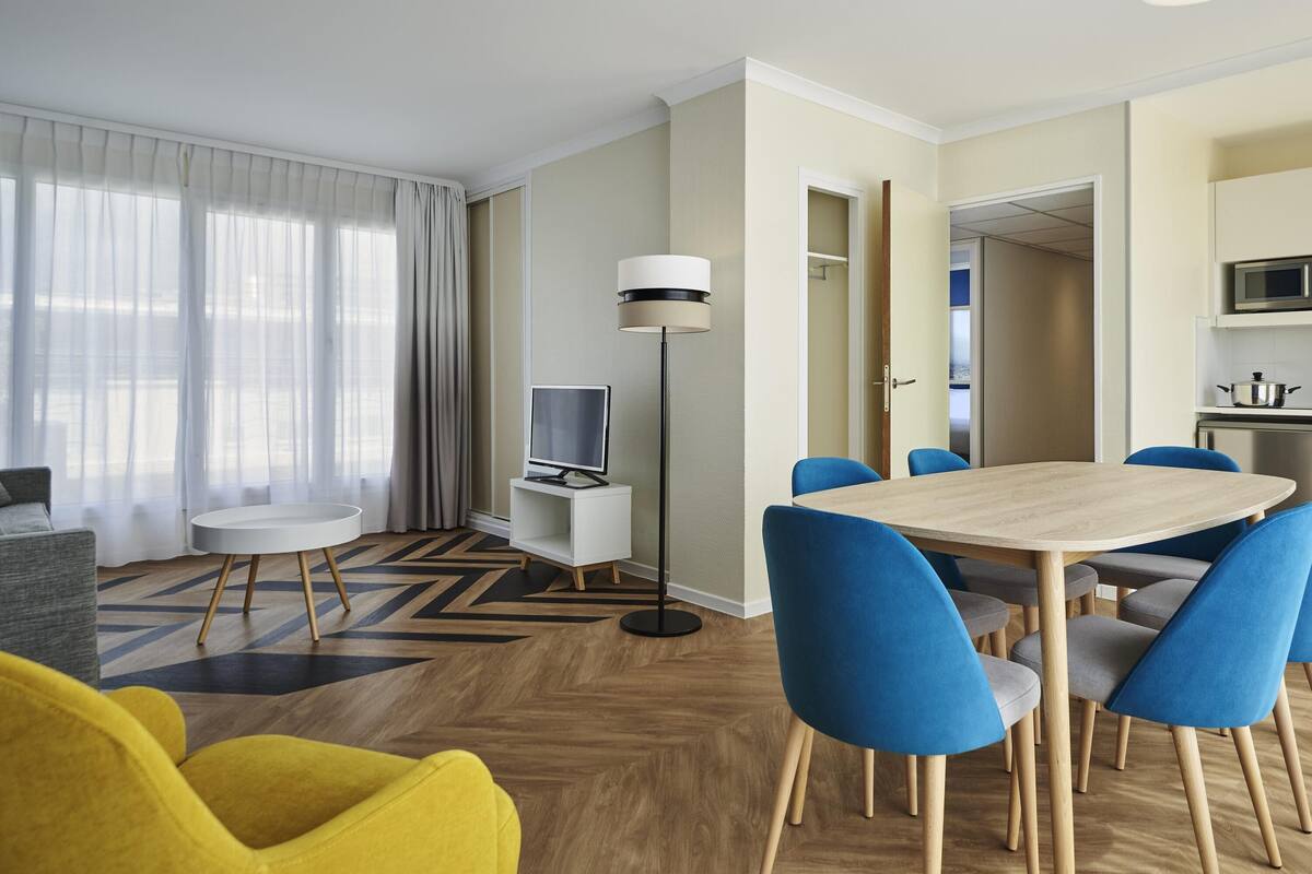 Une chambre d’hôtel moderne dotée d’un coin repas, d’un téléviseur à écran plat, d’un four à micro-ondes et offrant une vue sur l’extérieur par une porte.