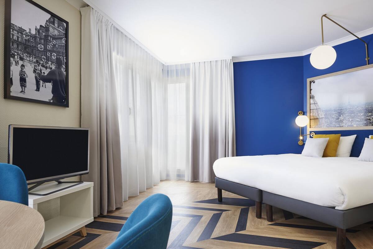 Une chambre d’hôtel avec un lit, une télévision, un bureau et une chaise.