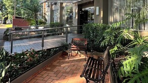 A paved outdoor area with a bench, potted plants, and a building with multiple air conditioning units.