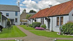A traditional white building with a red-tiled roof, a paved pathway, and well-maintained gardens. - The Inn at Lathones (Leven)