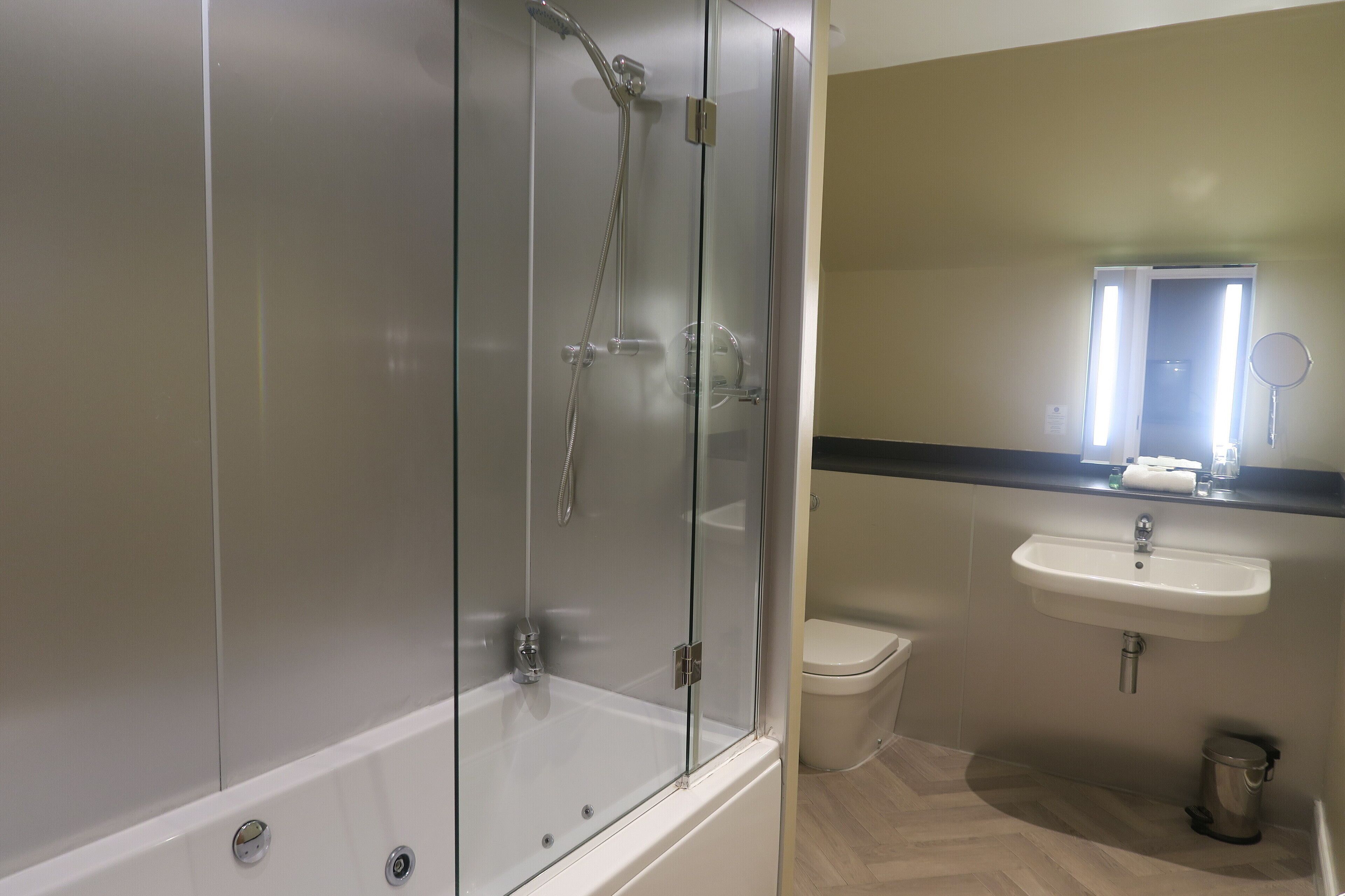 A bathroom with a glass-enclosed shower, a white sink, and a toilet.
