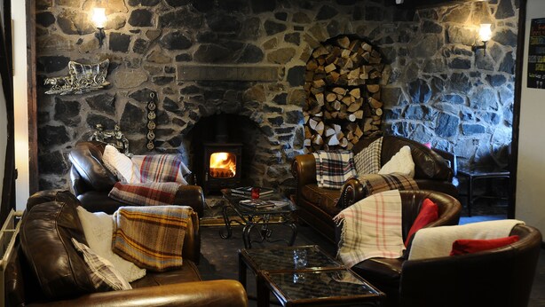 A cozy room with a stone fireplace, leather sofas, and a glass coffee table. - The Inn at Lathones (Leven)