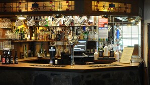 A bar with a variety of bottles and glasses, a Guinness tap, and a sale sign. - The Inn at Lathones (Leven)