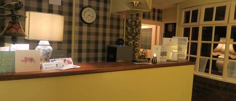 A reception desk with a clock, a lamp, and various informational materials.