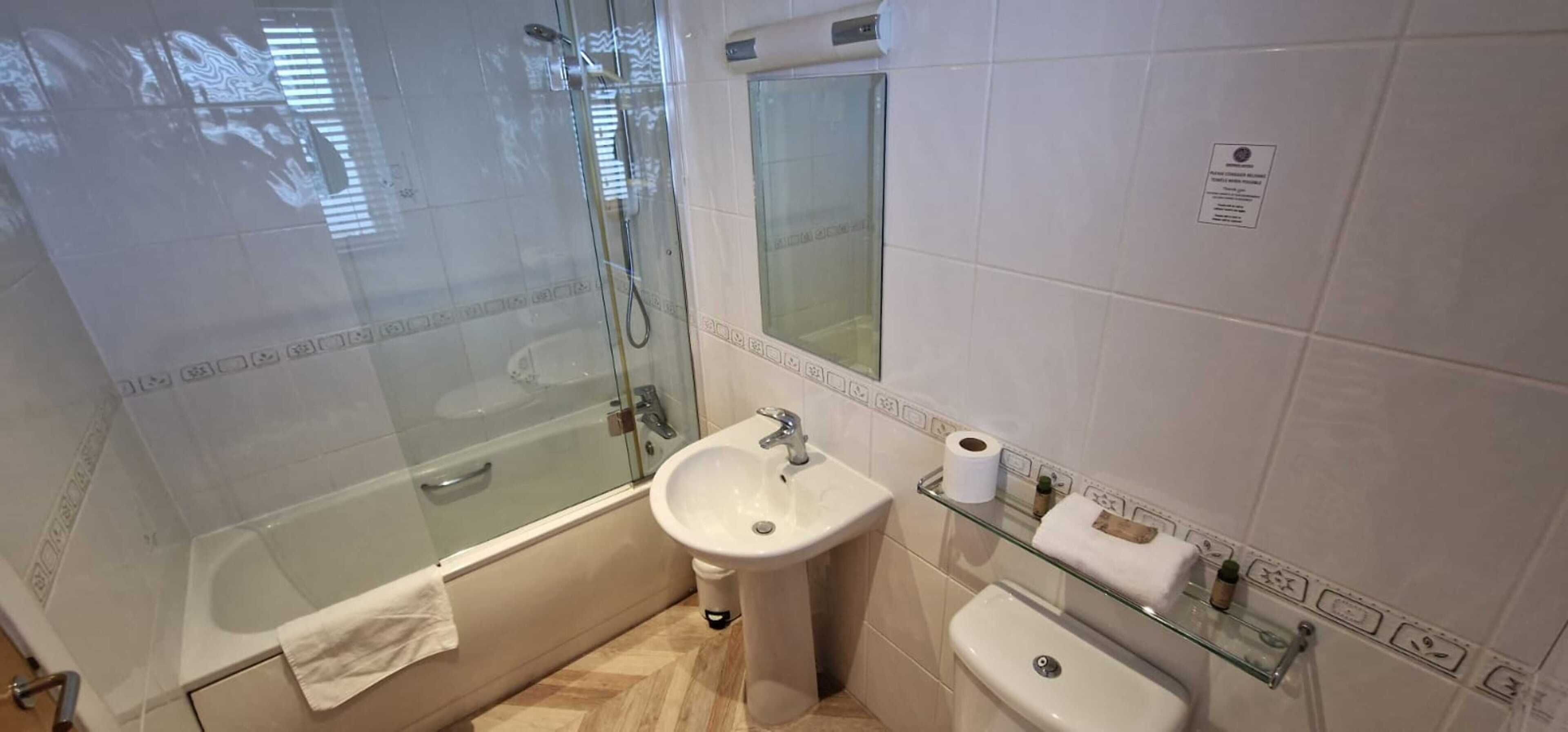 A bathroom with a glass-enclosed shower, a sink, and a toilet.