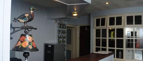 A kitchen with a wooden countertop, a decorative bird, a floral lamp, and a refrigerator.