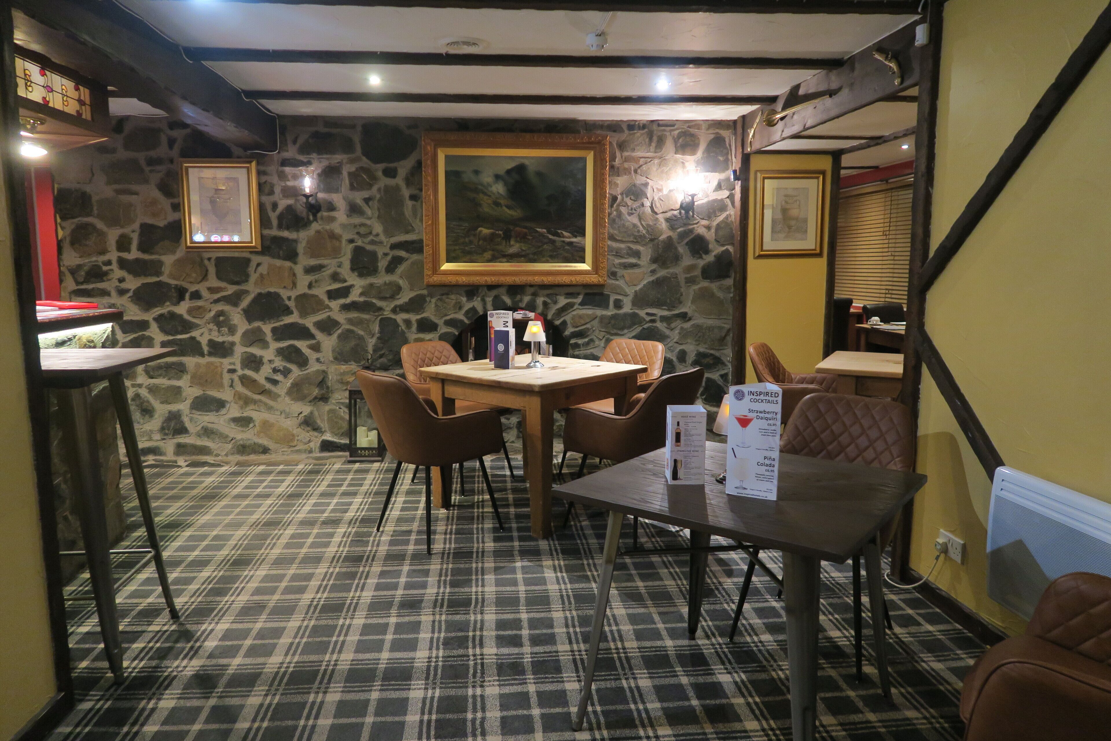 A cozy dining area with a stone wall, wooden table, and plaid carpet.