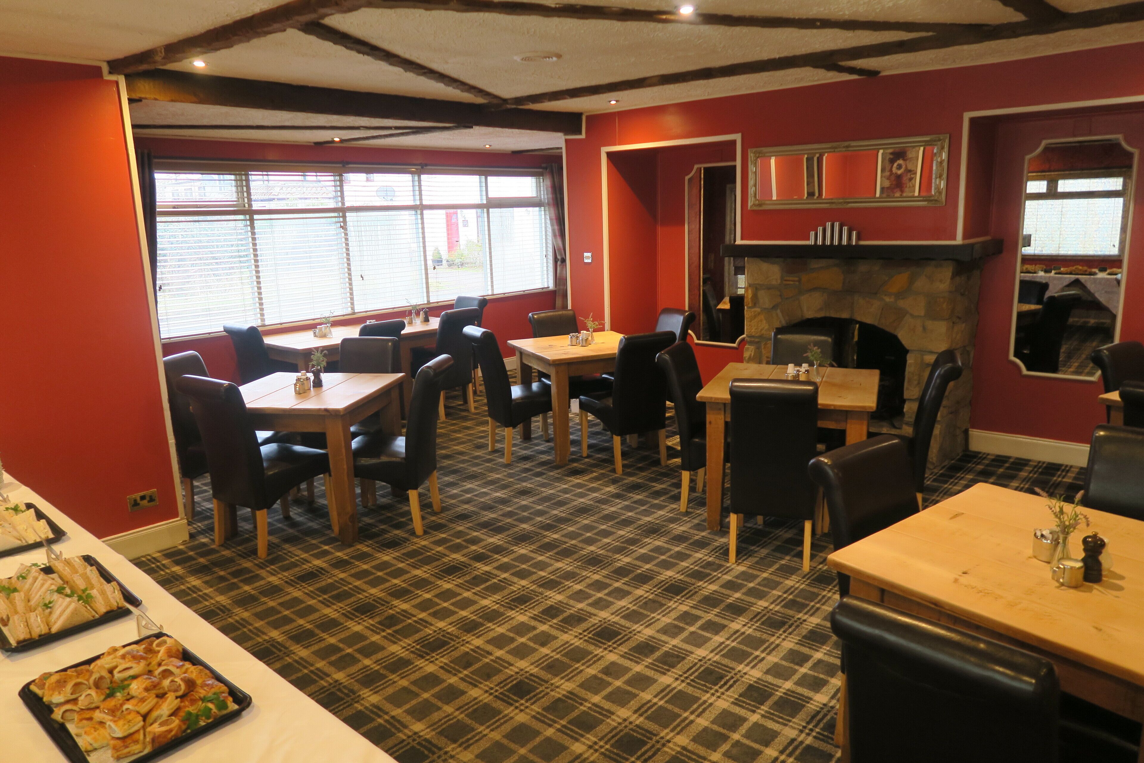 A dining area with tables and chairs, a fireplace, and a window with blinds.